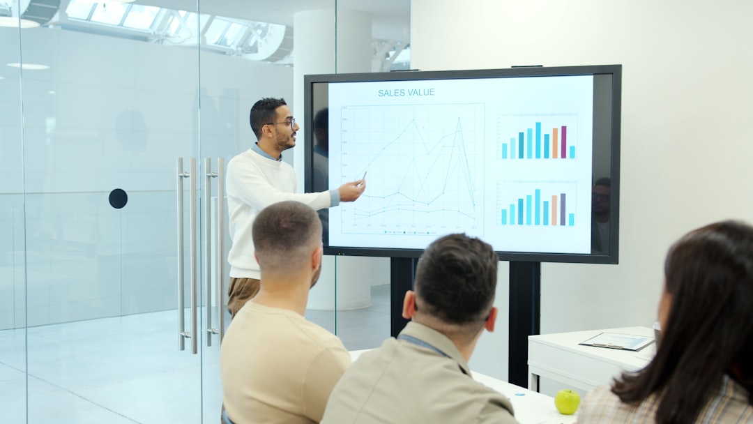 Photo by Vitaly Gariev Man presenting charts on a large screen to audience.